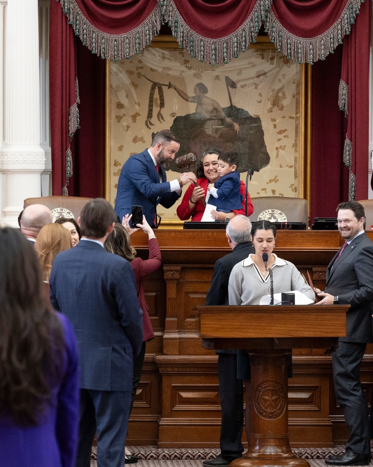 Denise receives the gavel from Speaker Zeke on the dais of the Texas House while holding her son Zeke.